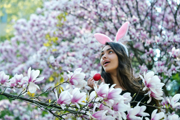 girl with easter egg, in bunny ears, magnolia - Foto, Bild