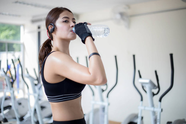 Deportiva mujer asia beber agua después de los ejercicios en el gimnasio. Ajuste
 - Foto, Imagen