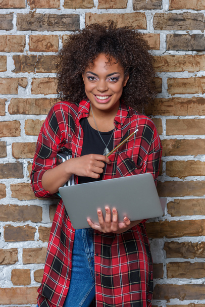 giovane donna afroamericana sorridente e con in mano un computer portatile
 - Foto, immagini