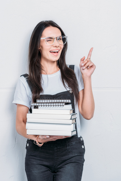 joven estudiante caucásico sosteniendo libros y señalando con el dedo
 - Foto, Imagen