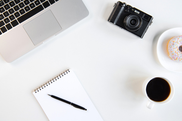 Felülnézet, laptop, üres jegyzetfüzet, toll, a kávé és a kamera a munkahelyen - Fotó, kép