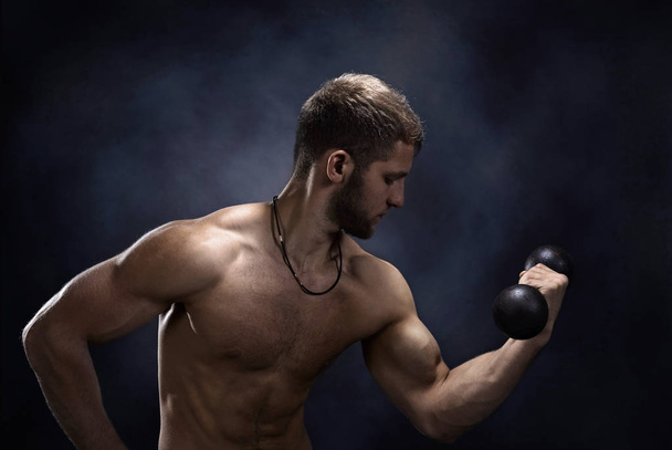 Jonge bodybuilder op een zwarte achtergrond  - Foto, afbeelding