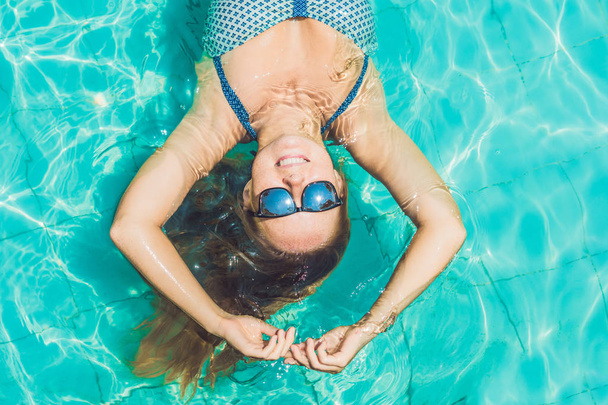 Beautiful young woman floating in pool - 写真・画像