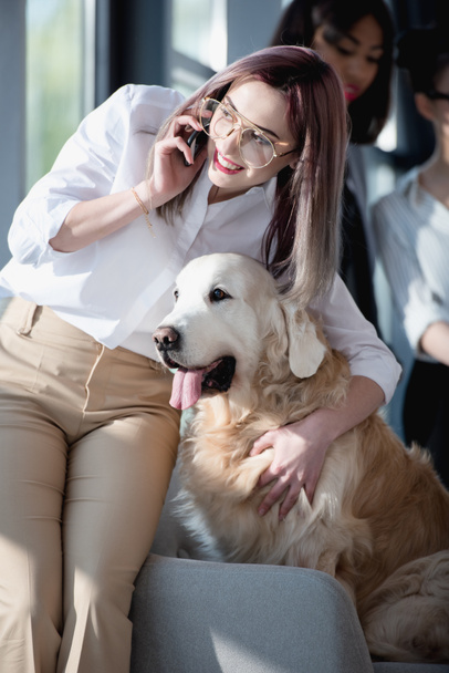 businesswoman talking on smartphone and hugging dog - Photo, image