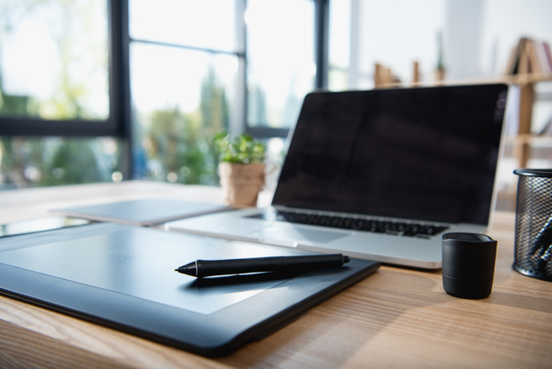 ноутбук с графическим планшетом на столе в офисе
 - Фото, изображение