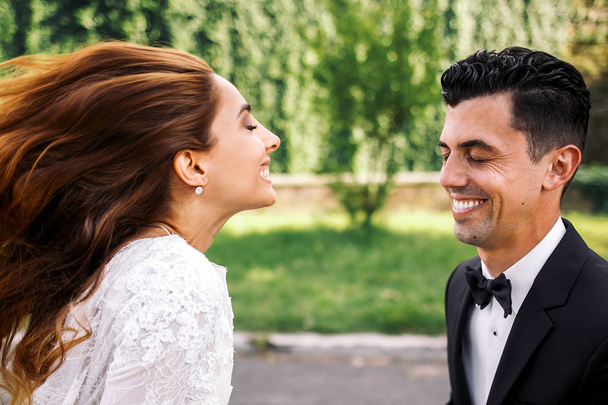 Wind blows bride's hair away while she smiles to groom - Фото, зображення
