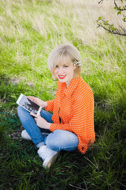 portret na zewnątrz młode piękne dziewczyny w pomarańczowy hipster blond jasny wesoły dot bluzka, uśmiechając się czerwone usta pulchna na tle zielonej trawy z laptopa - Zdjęcie, obraz