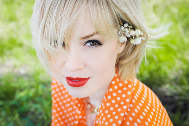 портрет на открытом воздухе молодая красивая девушка в оранжевом хипстера блондинка яркий веселый горошек блузка, улыбающиеся красные пухлые губы на фоне зеленой травы
 - Фото, изображение