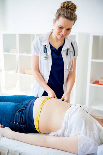Doctor checking pregnant woman with measuring tape - Photo, image
