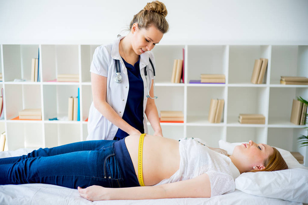 Lekarz, sprawdzanie Kobieta w ciąży z taśma pomiarowa - Zdjęcie, obraz