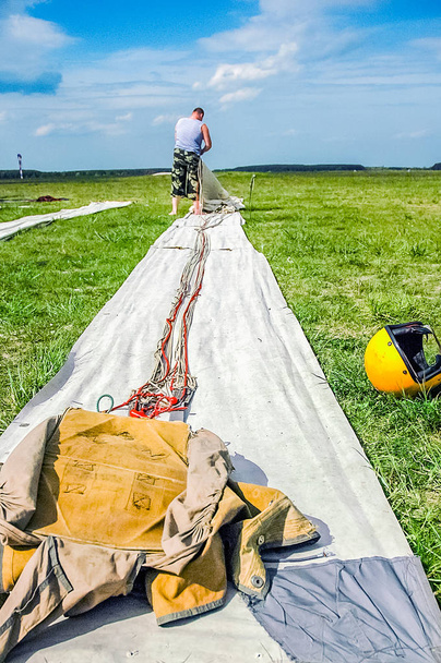Un hombre, un paracaidista, se acumula en la hierba, un paracaídas, para un
 - Foto, Imagen