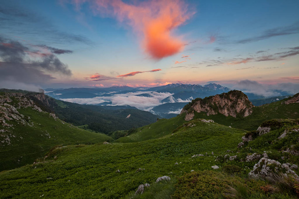 Bergdal bedekt met wolken bij zonsondergang - Foto, afbeelding