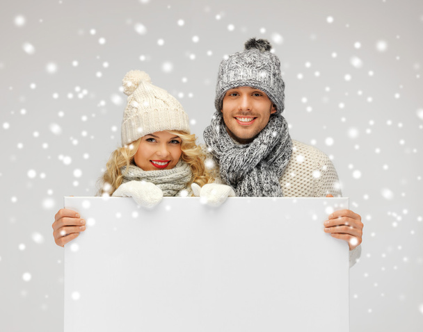 Couple in a winter clothes holding blank board - Φωτογραφία, εικόνα