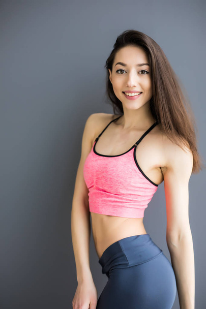 Gri bir arka plan üzerinde izole duran güzel fitness kadın - Fotoğraf, Görsel
