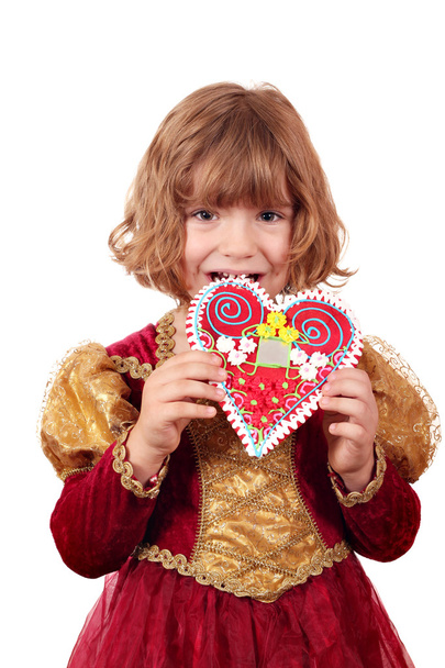 Little girl eating gingerbread heart - Foto, imagen