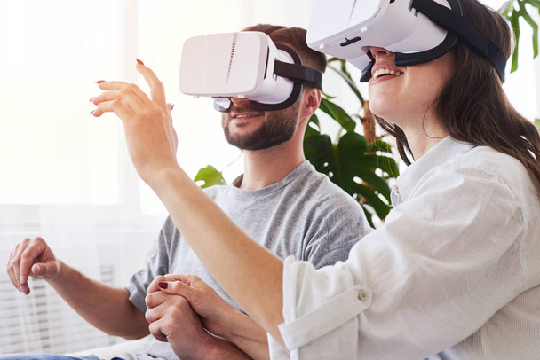 Woman and man in VR goggles holding hands and orienting in space - Foto, Bild