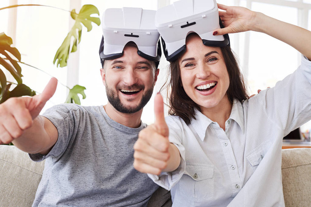 Smiling pair in VR goggles showing thumbs up - Zdjęcie, obraz