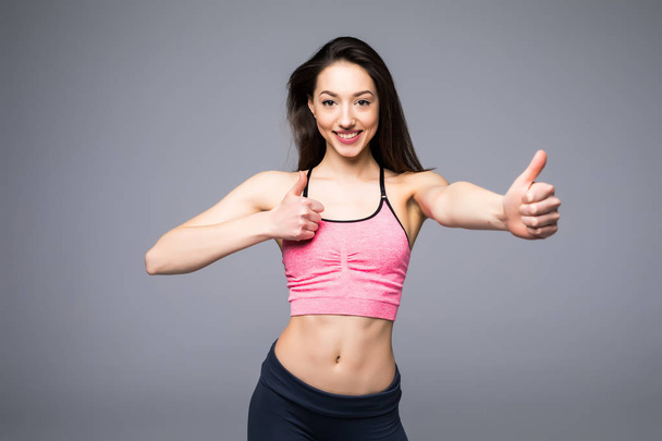Bella donna fitness mostrando pollice su sfondo bianco
 - Foto, immagini