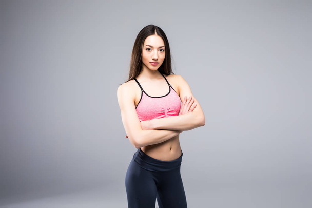Fitness woman in sports clothes posing on gray background, studio shot - Photo, Image