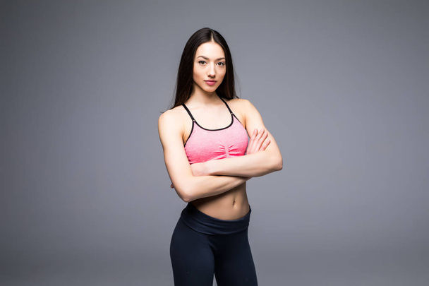 Fitness woman in sports clothes posing on gray background, studio shot - Φωτογραφία, εικόνα