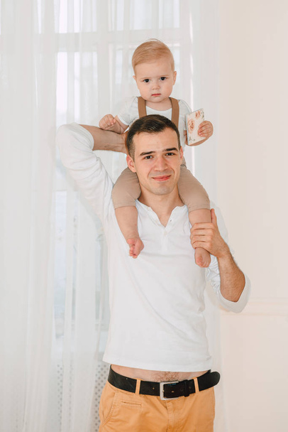 ハンサムな父親と息子 1 歳楽しんで幸せと一日の時間にスタジオに抱いて笑顔の肖像画。フレンドリーな家族の概念. - 写真・画像