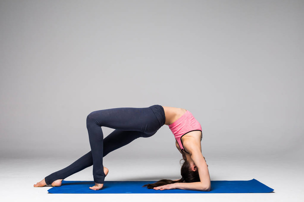 Молодая привлекательная женщина практикует йогу, стоя в различных упражнениях йоги, носить спортивную одежду изолированы на сером фоне. Концепция позиции йоги
 - Фото, изображение