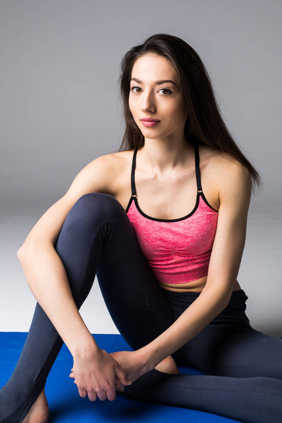 Young attractive woman practicing yoga, standing in different yoga exercise, wearing sportswear isolated on grey background. Series of Yoga position concept - Foto, afbeelding