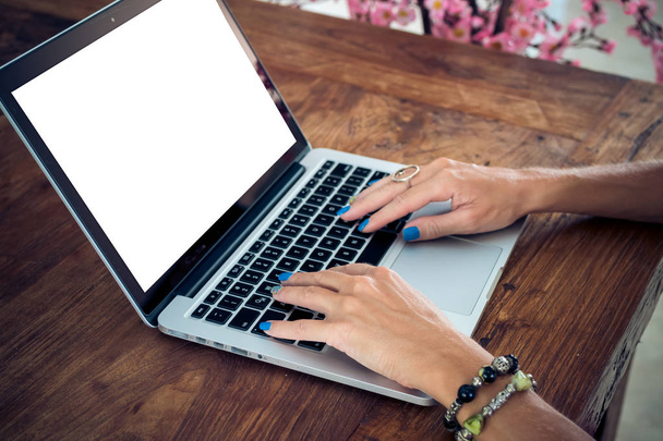 Atrakcyjna kobieta studentka za pomocą laptopa na drewnianym stole. Biały ekran, wolna przestrzeń. - Zdjęcie, obraz