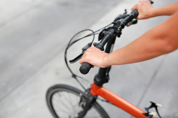 Woman riding a bicycle. Closeup on handlebar with female hand. Healthy lifestyle and sport concept - Foto, imagen