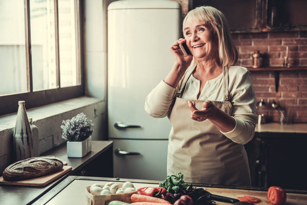 Old woman in kitchen - Фото, изображение