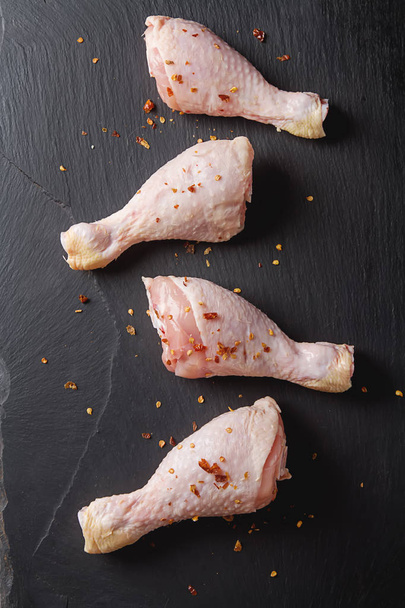 Chicken legs on a black background. Lunch on the grill. Top view - Foto, Imagem