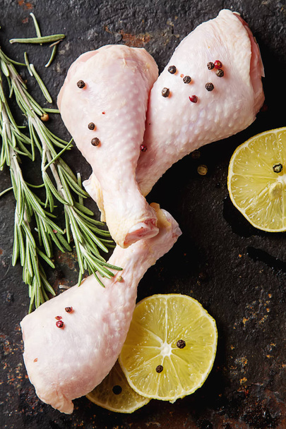 Chicken legs with rosemary, pepper and lemon. Dark background. L - 写真・画像