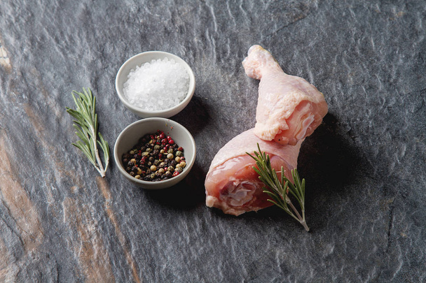 Chicken legs with rosemary and spices. Dark background. Lunch on - Zdjęcie, obraz