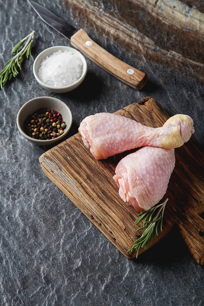 Chicken legs with rosemary and spices. Dark background. Lunch on - Zdjęcie, obraz