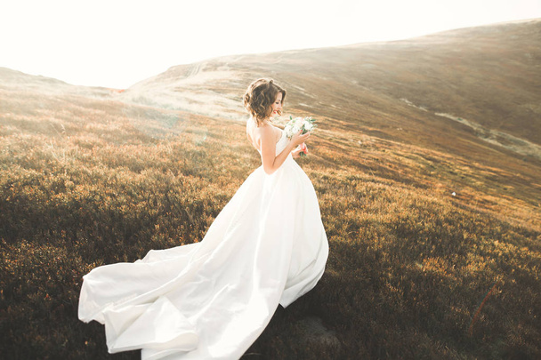 Happy beautiful young bride outside on a summer meadow at the sunset - Fotoğraf, Görsel