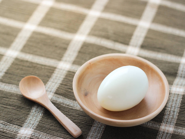 Boiled egg in small wood dish and spoon  - Fotoğraf, Görsel