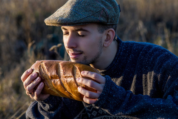 Young guy sniffs fresh bread outdoor - Photo, Image
