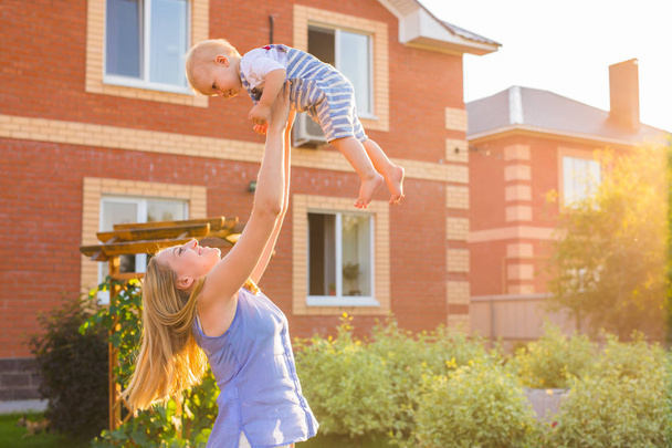 Onnellinen harmoninen perhe ulkona. äiti heittää vauvan ylös, nauraa ja leikkii kesällä luonnossa. - Valokuva, kuva