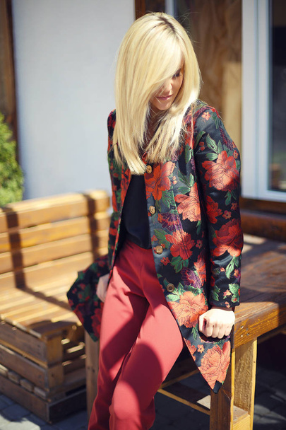 young beautiful stylish woman posing on street in floral printed - Фото, изображение