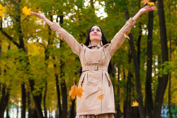 glückliche brünette Frau wirft Herbstblätter nach oben - Foto, Bild