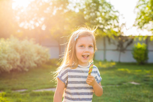 Funny child with candy lollipop, happy little girl eating big sugar lollipop, kid eat sweets - Foto, Bild