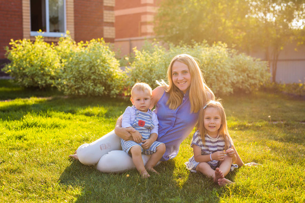 Onnellinen äiti ja kaksi lasta puutarhassa
. - Valokuva, kuva