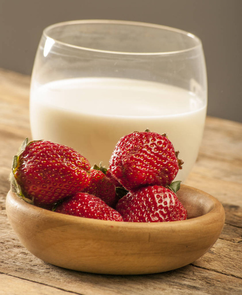 glass of milk with strawberries in bowl on table - Photo, Image