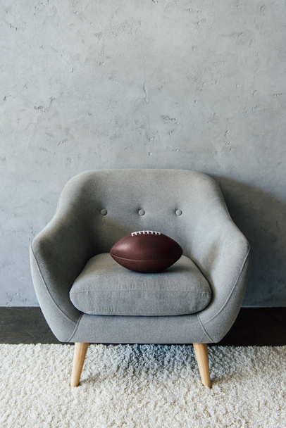 american football ball on grey armchair - Fotoğraf, Görsel