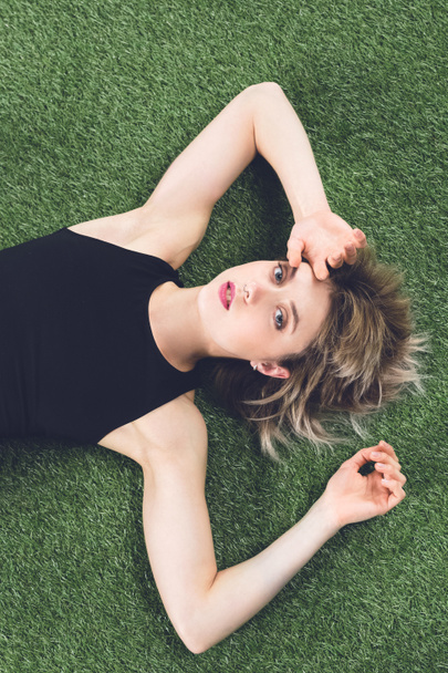 молода біла жінка лежить на траві
 - Фото, зображення