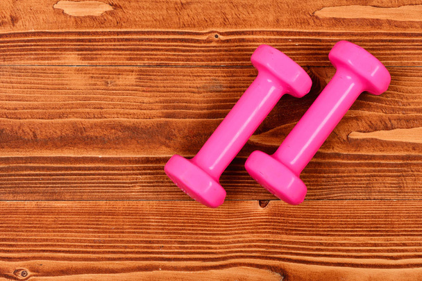 dumbbells in pink color for fitness on brown vintage wooden - Zdjęcie, obraz