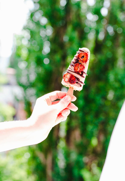 Hand holding a ice cream popsicles with chocolate and strawberri - Φωτογραφία, εικόνα