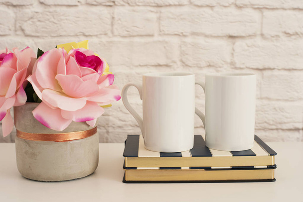 Two Mugs. White Mugs Mockup. Blank White Coffee Mug Mock Up. Styled Photography. Coffee Cup Product Display. Two Coffee Mugs On Striped Design Notebooks. Vase With Pink Roses - Φωτογραφία, εικόνα