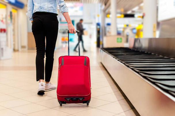 空港のベルトコンベアから鞄を取り戻す女性 - 写真・画像