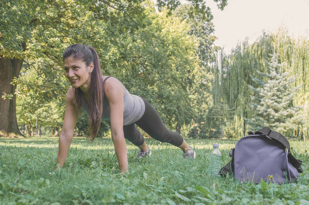 Νεαρή γυναίκα άσκηση - κάνει μια σανίδα στη φύση - Φωτογραφία, εικόνα